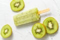 Frozen kiwi fruit ice or sorbet or popsicle with slices on white cement Royalty Free Stock Photo