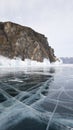 Frozen lake Baikal in Russia. Beautiful rock, bright large cracks on the surface of the lake and the ice blocks near the shore.