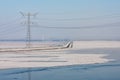 Frozen lake covered with haze and view at power pylon