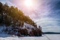 Frozen lake covered with snow with rocky shores