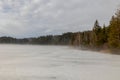 Frozen lake in dense fog with trees on the shore in Upper Bavaria in winter Royalty Free Stock Photo