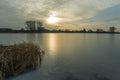 Frozen lake with dry reeds, sunset and clouds on the sky Royalty Free Stock Photo