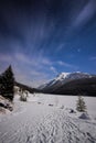 Frozen lake and snowy path in mountains during cold night under sky full of stars and faslty flowing clouds, Two Jack Lake, Banff, Royalty Free Stock Photo