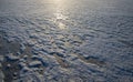 Frozen lake surface with uneven snow texture and sunlight reflection during winter Royalty Free Stock Photo