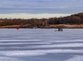 Ice fishing; frozen lake surface in winter with two ice shanties or huts on the frozen lake. Royalty Free Stock Photo