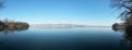 Frozen lake in winter season close to the village with forest reflecting in water