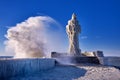 Frozen lighthouse and pier on stormy winter day