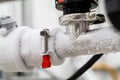 Frozen liquid nitrogen carrying pipes with a valve and black plastic lever close up in a science laboratory