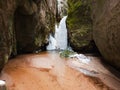 Frozen Little Adrspach waterfall. Red sand, snow and icicles on rocks