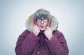 Frozen man in glasses and winter clothes warming ears, cold, snow, blizzard Royalty Free Stock Photo