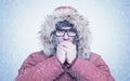 Frozen man in red winter clothes and glasses warming hands, cold, snow, frost, blizzard Royalty Free Stock Photo