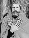 Frozen man with squinty eyes , bearded hipster, with beard and moustache covered with white frost wrapped in orange