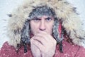 Frozen man in winter clothes warming hands, cold, snow, blizzard Royalty Free Stock Photo