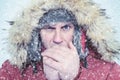 Frozen man in winter clothes warming hands, cold, snow, blizzard Royalty Free Stock Photo