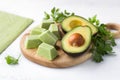 Frozen mashed avocado in portions and a thin layer with fresh avocado and parsley on a light blue background. Seasonal home