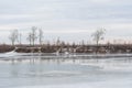 Frozen melting winter river shore with trees on the other side Royalty Free Stock Photo