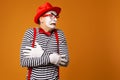 Frozen mime man in red hat and striped t-shirt on blank orange background