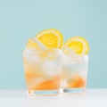 Frozen oranges alcohol drinks with orange liquor, sliced fruit, ice cubes in misted shot glass on blue pastel background, square. Royalty Free Stock Photo