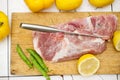 Frozen piece of meat, yellow lemon and green peas pod on a wooden cutting board