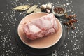 Frozen piece of raw meat on plate on black table. Rime on product, thawing