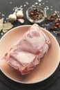 Frozen piece of raw meat on plate on black table. Rime on product, thawing