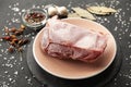Frozen piece of raw meat on plate on black table. Rime on product, thawing