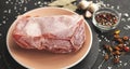 Frozen piece of raw meat on plate on black table. Rime on product, thawing