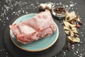 Frozen piece of raw meat on plate on black table. Rime on product, thawing