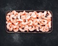 Frozen pilled prawns with ice cubes on a black plate on a black background Royalty Free Stock Photo