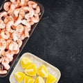 Frozen pilled prawns and lemon slices on a black background Royalty Free Stock Photo