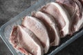 Frozen pork chops in plastic tray packaging thawing.