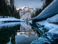 Frozen Pragser Wildsee lake surrounded by trees covered with snow in South Tyrol, Italy