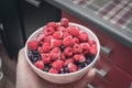 Frozen raspberries and blueberries in a bowl held by a man's hand. Preservation of vitamins for a long time during Royalty Free Stock Photo