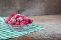 Frozen raspberries in a glass dessert bowl on the white and green checked napkin. Royalty Free Stock Photo