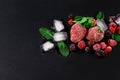 Frozen raspberry, blackberry, strawberries mint leaves, pieces of ice on a black shale board, frozen fruit, top view, close up, pl Royalty Free Stock Photo