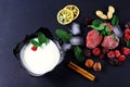 Frozen raspberry, blackberry, strawberries, yoghurt plate mint leaves, pieces of ice on a black shale board, slices of lemon, nuts Royalty Free Stock Photo