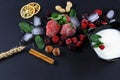 Frozen raspberry, blackberry, strawberries, yoghurt plate mint leaves, pieces of ice on a black shale board, slices of lemon, nuts Royalty Free Stock Photo