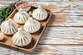 Frozen Raw dumplings Khinkali with beef and lamb meat on wooden tray with herbs. White wooden background. Top view. Copy Royalty Free Stock Photo