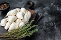 Frozen raw dumplings pierogi with potato on a wooden board. Black background. Top View. Copy space Royalty Free Stock Photo