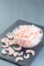 Frozen raw peeled shrimps in a glass bowl on a dark background, vertical, copy space Royalty Free Stock Photo