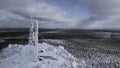 Frozen repeater antenna on the top of a hill in winter. Clip. Aerial view of winter valley panorama and blue cloudy sky. Royalty Free Stock Photo