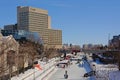 Frozen rideau canal with skaters, food stalls and highrise office buildings on the embankment