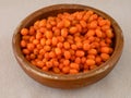 Frozen ripe sea buckthorn berries (Hippophae) in a wooden bowl