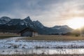 Frozen river and cottage in the Alps at sunset