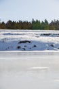 Frozen river on a sunny day. A forest grows on the shore Royalty Free Stock Photo