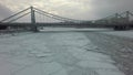 A frozen river surface and a bridge above it in the middle of a winter urbanscape