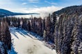 Frozen river in a winter forest leads to a lake