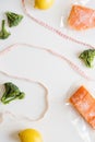 Frozen salmon fish fillets in plastic package, fresh broccoli florets, lemons and measuring tape