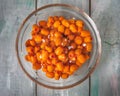 Frozen sea buckthorn berries in a deep glass plate on a wooden background Royalty Free Stock Photo