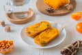 Frozen sea buckthorn briquettes with herbs and tangerine slices for instant hot sea buckthorn tea on a white plate on a light